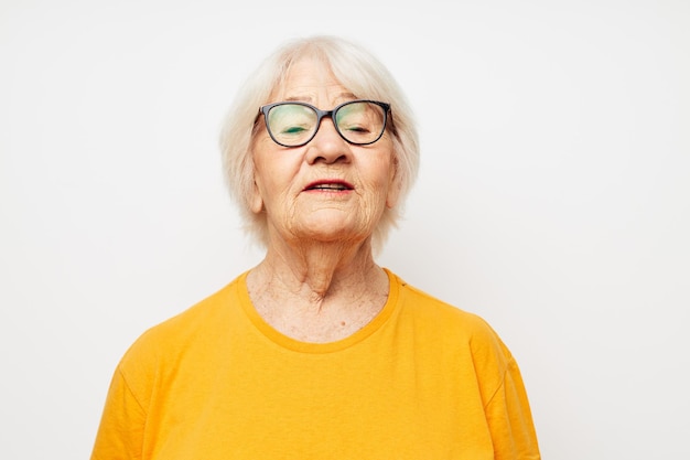 La donna anziana emotiva in maglietta casual e occhiali ha isolato lo sfondo