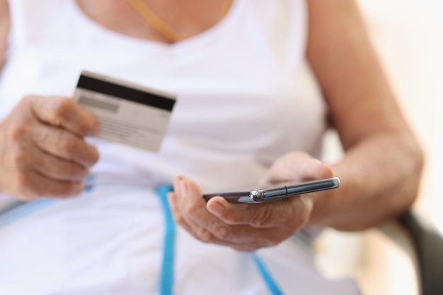 La donna anziana fa acquisti su internet su smartphone e paga con il fondo pensione della carta di credito