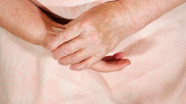 La donna anziana sonda le sue dita. Primo piano delle mani