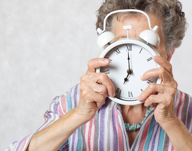 La donna anziana tra i 70 e gli 80 anni mostra una sveglia vintage