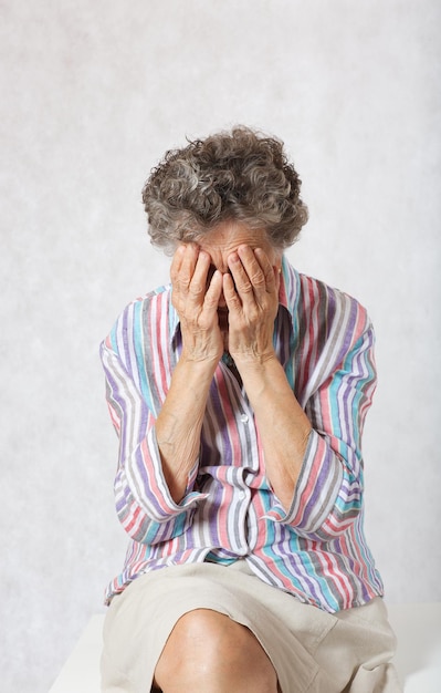 La donna anziana tra i 70 e gli 80 anni si copre il volto.