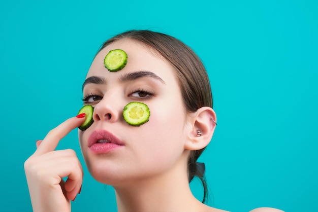 La donna applica la maschera facciale isolata su sfondo blu studio spa maschera cosmetica bella donna con