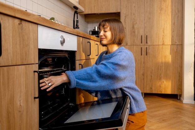 La donna apre un forno in cucina