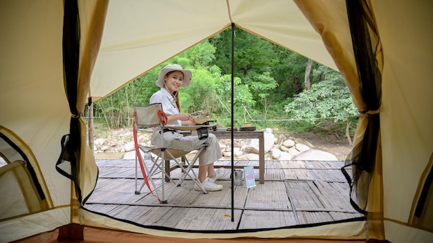 La donna asiatica attraente si diverte in campeggio da sola nel bellissimo campeggio nella natura selvaggia