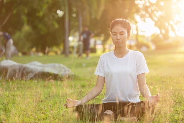 La donna asiatica che fa l'yoga si esercita nel parco