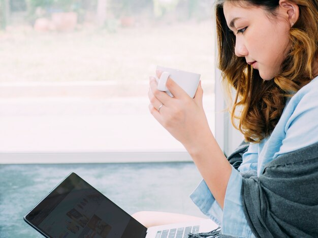 La donna asiatica di affari fa il suo lavoro a casa usando Internet in linea