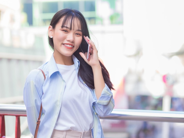 La donna asiatica di affari professionale sta camminando verso l'ufficio o il posto di lavoro mentre tiene colloqui con il cliente.