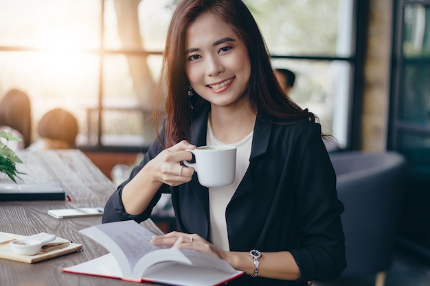 La donna asiatica di affari sta lavorando e sta bevendo il caffè a tempo di rilassamento