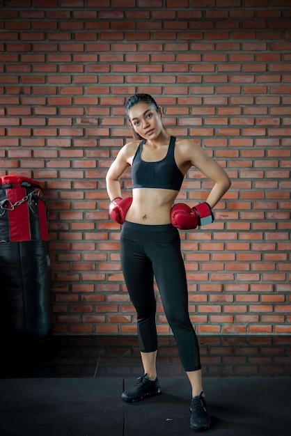 La donna asiatica di sport indossa il guantone da boxe in palestraLa gente della Tailandia si allena Il meglio del combattenteDonna forte