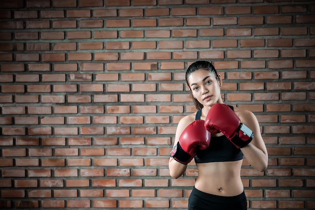 La donna asiatica di sport indossa il guantone da boxe in palestraLa gente della Tailandia si allena Il meglio del combattenteDonna forte