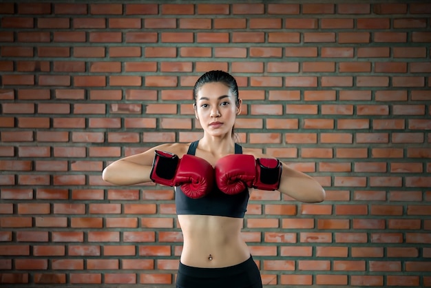 La donna asiatica di sport indossa il guantone da boxe in palestraLa gente della Tailandia si allena Il meglio del combattenteDonna forte