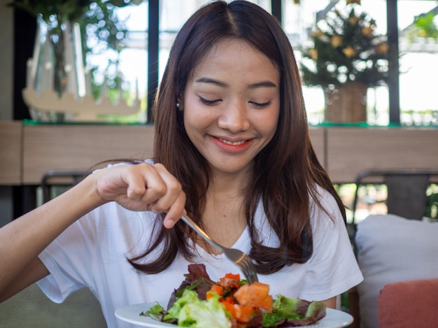 La donna asiatica è felice di mangiare insalata di salmone