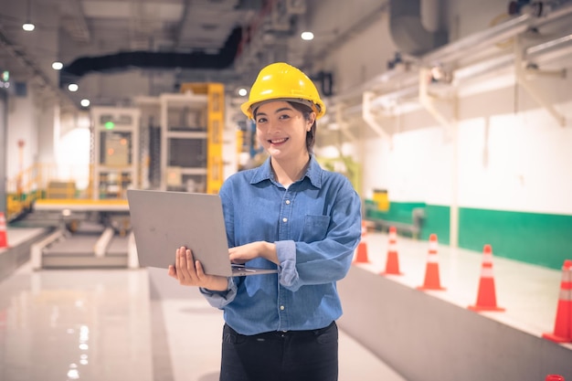 La donna asiatica è un ingegnere che ispeziona la macchina in fabbrica con il computer Ingegnere donna asiatica che lavora nel concetto di fabbrica