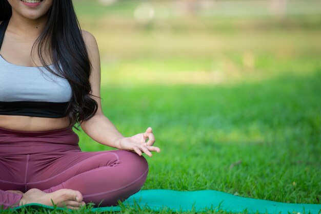 La donna asiatica gioca a yoga al parco