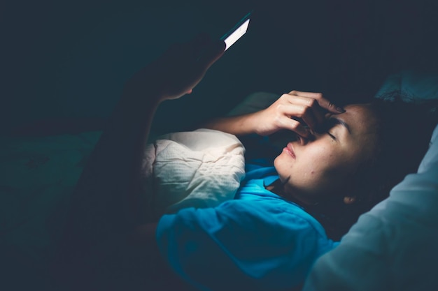 La donna asiatica gioca con lo smartphone nel letto di notte. Persone della Thailandia. Dipendenti dai social media. Gioca a Internet tutta la notte. Licnobite