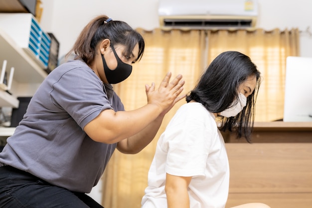 La donna asiatica in quarantena fa il massaggio a casa con la maschera