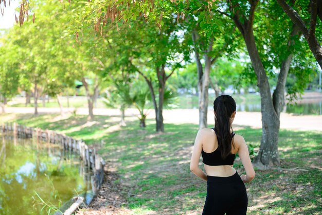 La donna asiatica in reggiseno sportivo nero riscalda il corpo preparandosi per gli esercizi di joggingyoga per la vita