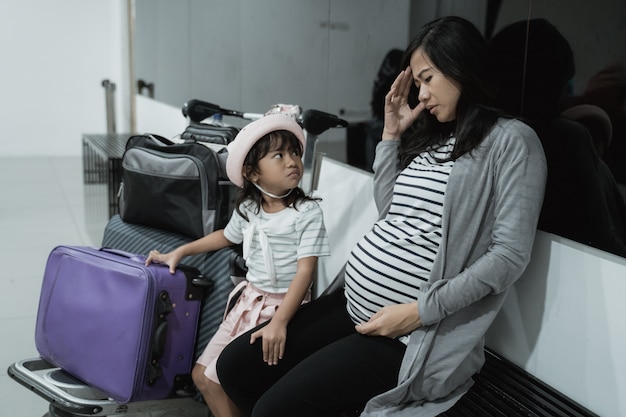 La donna asiatica incinta ha le vertigini e sua figlia quando si trovano nell'aeroporto della sala d'aspetto