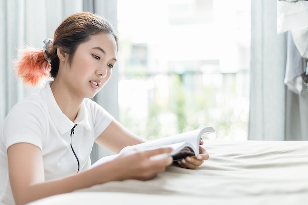 La donna asiatica legge un libro analogico sul divano.