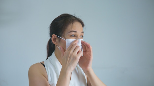 La donna asiatica nella mascherina medica resta l'isolamento a casa per l'auto quarantena.