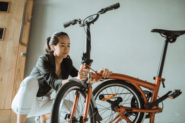 La donna asiatica prepara una bici pieghevole da casa sua per andare al lavoro