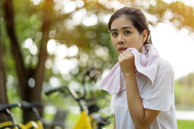 La donna asiatica prova ad esercitare e sedersi il resto con l&#39;asciugamano della tenuta al parco