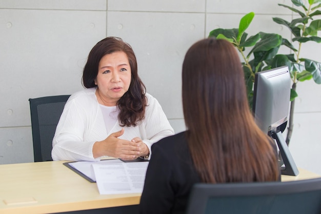 La donna asiatica si siede sulla sedia mentre il colloquio di lavoro con il dirigente d'azienda nella stanza dell'ufficio