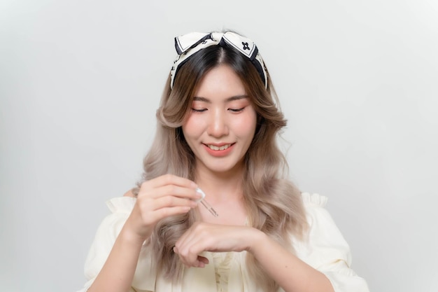 La donna asiatica sta interrompendo i sieri per la pelle per la sua mano per rendere la pelle morbida, idratata, bianca e chiara