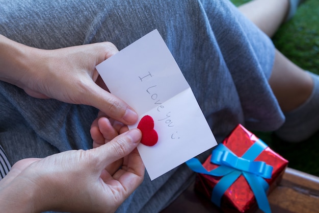 La donna asiatica sta leggendo la scheda del biglietto di S. Valentino con la confezione regalo