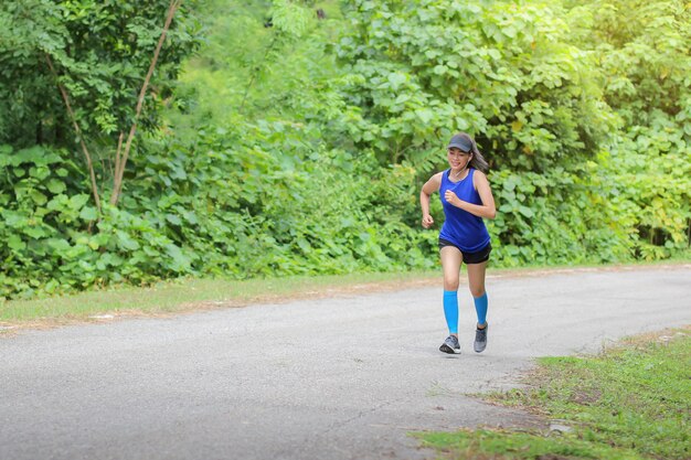 La donna asiatica stava facendo jogging sulla strada nella foresta.