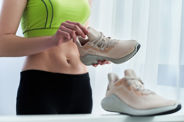 La donna atletica fitness in abiti sportivi detiene scarpe da ginnastica beige per fare jogging e correre allenamento. Fai sport e sii in forma. Sportivi con stile di vita sportivo sano