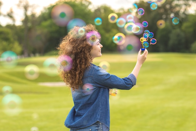 La donna attraente che fa le bolle nel parco