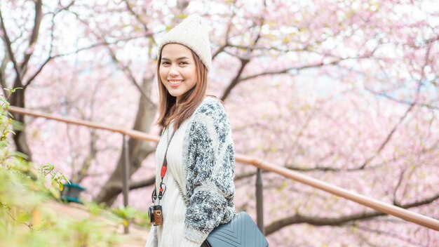 La donna attraente sta godendo con Cherry Blossom nel parco