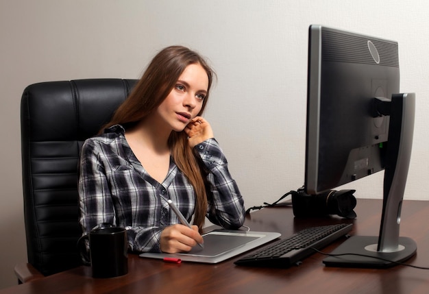 La donna attraente sta ritoccando le foto digitali che utilizzano il computer