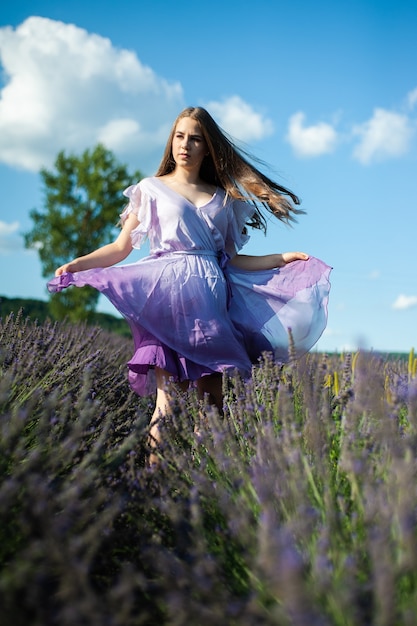 La donna attraente sul campo di lavanda si diverte