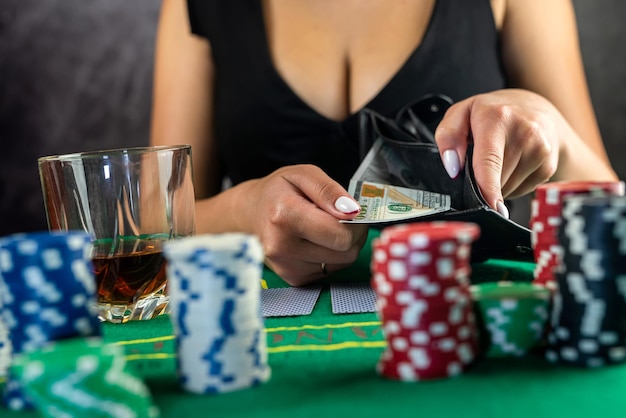 La donna avida del poker prende le fiches su una banconota da cento dollari dal tavolo dopo aver vinto il gioco