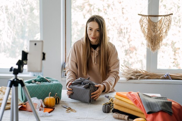 La donna avvolge il regalo furoshiki in stile zero waste e registra la master class di vlog sul cellulare furoshiki