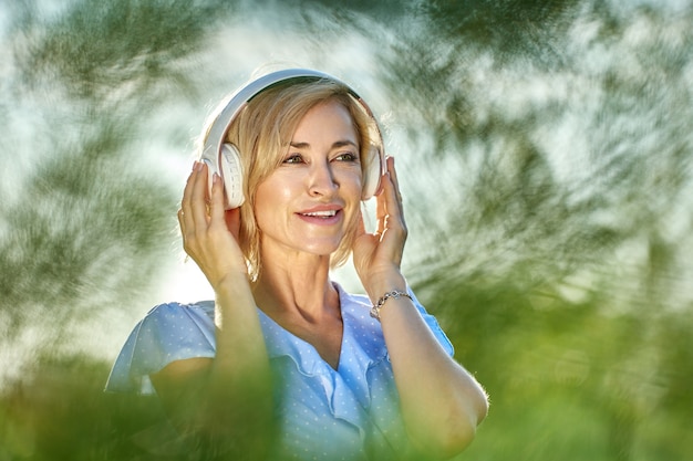 La donna bianca matura nella sua s ascolta musica usando le cuffie wireless