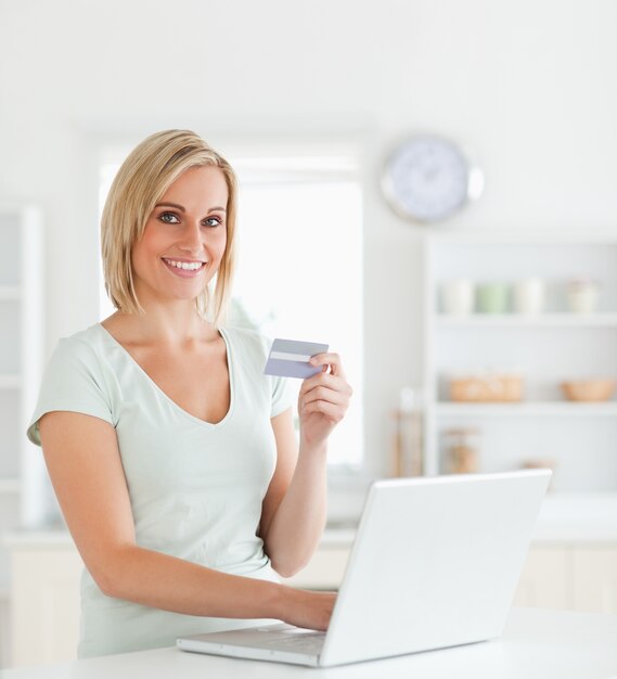 La donna bionda con la carta di credito e il taccuino esamina la macchina fotografica