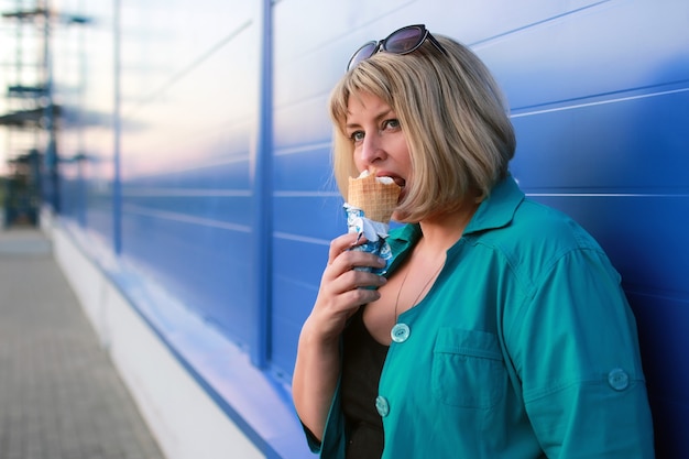 La donna bionda mangia il gelato all'aperto