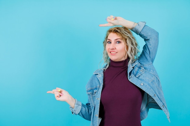 La donna bionda sorridente sta puntando a sinistra con gli indici su sfondo blu