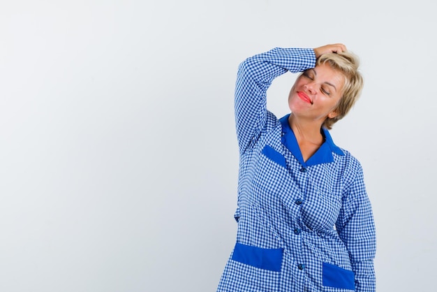 La donna bionda sta sognando mettendo la mano sulla testa su sfondo bianco