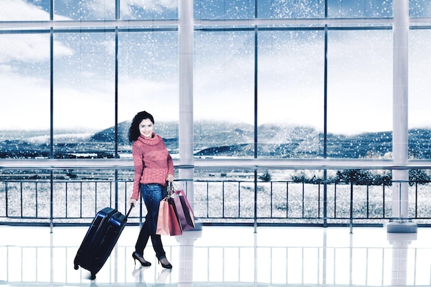 La donna cammina con le borse della spesa in aeroporto in inverno