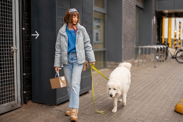 La donna cammina con un cane e un pacco su una strada