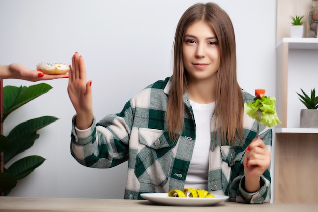 La donna carina fa una scelta tra cibo sano e dannoso