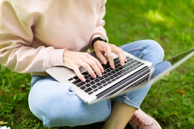 La donna caucasica abbastanza giovane è impegnata nel libero professionista nel parco con il computer portatile