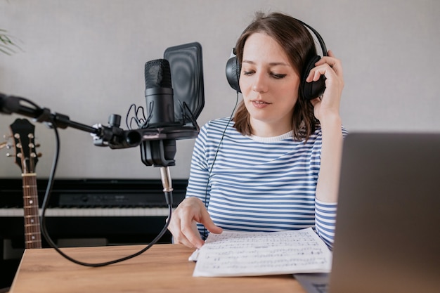 La donna caucasica elegante e istruita registra podcast in uno studio di registrazione o a casa sua il