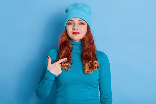 La donna caucasica soddisfatta con i capelli rossi indica se stessa