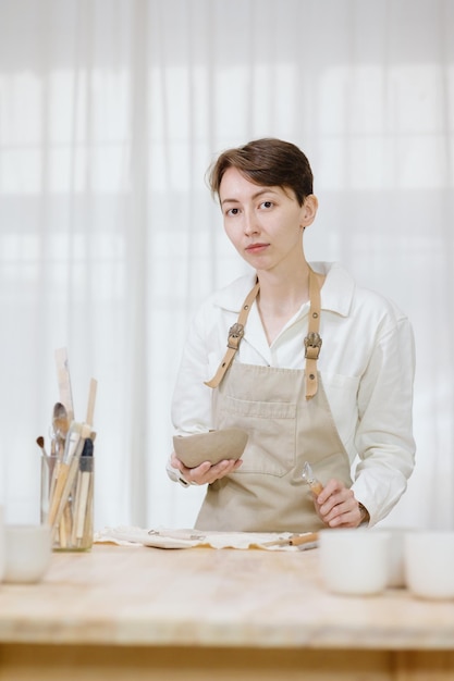 La donna ceramista nel laboratorio fa tazze di argilla per piccole imprese o hobby