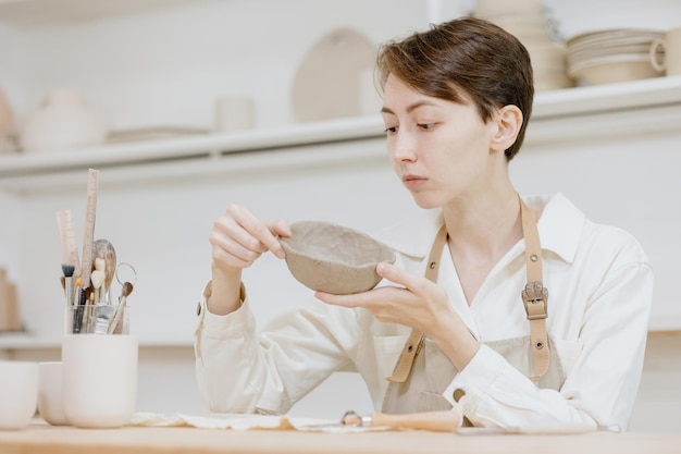 La donna ceramista nel laboratorio fa tazze di argilla per piccole imprese o hobby